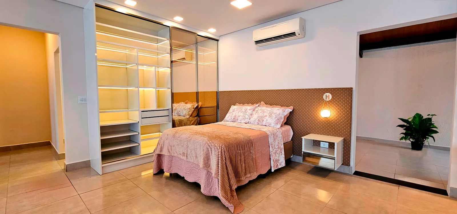 Closet planejado em alumínio com iluminação interna e portas espelhadas